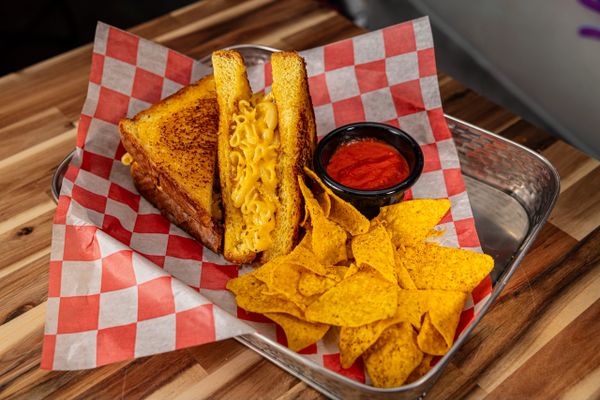 grilled Mac and cheese with side of tomato dipping sauce in dish lined with checkered paper