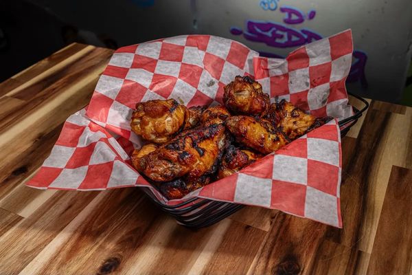 char buffed chicken wings in a dish lined with checkered paper