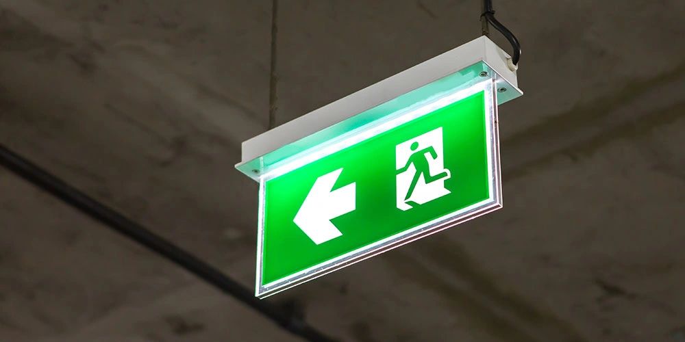Illuminated green emergency exit sign pointing left.