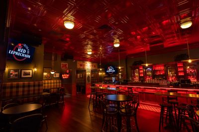 Cozy pub interior with warm red lighting and wooden furniture.