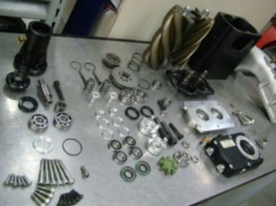 A supercharger disassembled, showing all of the parts: rotors, bearings, seals, font plate, bolts, e