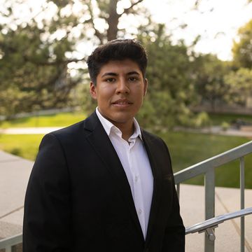 Young man in a black suit outdoors.