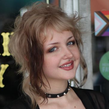 Young woman with shag haircut and choker smiles.