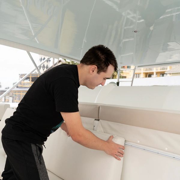 Man arranging cushions on a boat seating area.
