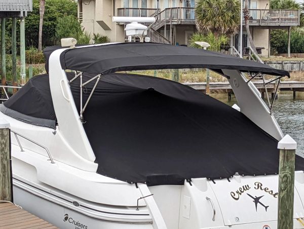 White motorboat docked, covered with black canvas and canopy.