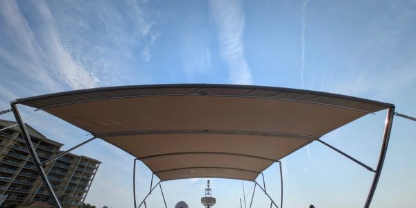 Boat canopy against a blue sky with wispy clouds.