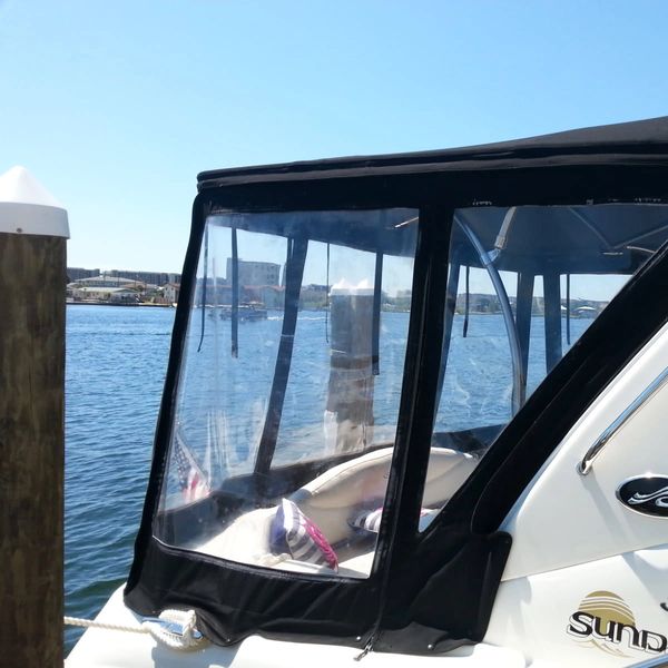 Boat with black canopy docked by the water.