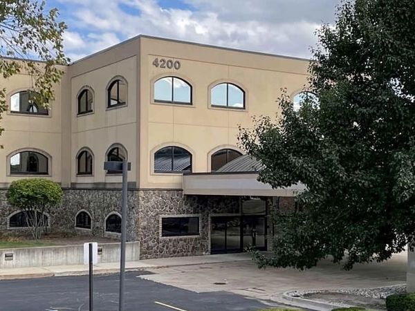 Office building with stone and beige exterior and arched windows.