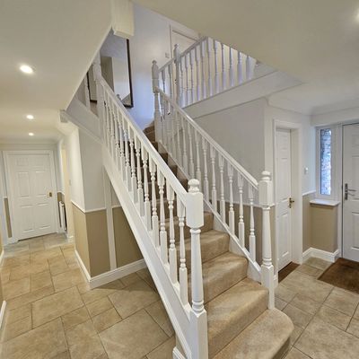 Bright hallway with white wooden staircase and beige tiled floor.