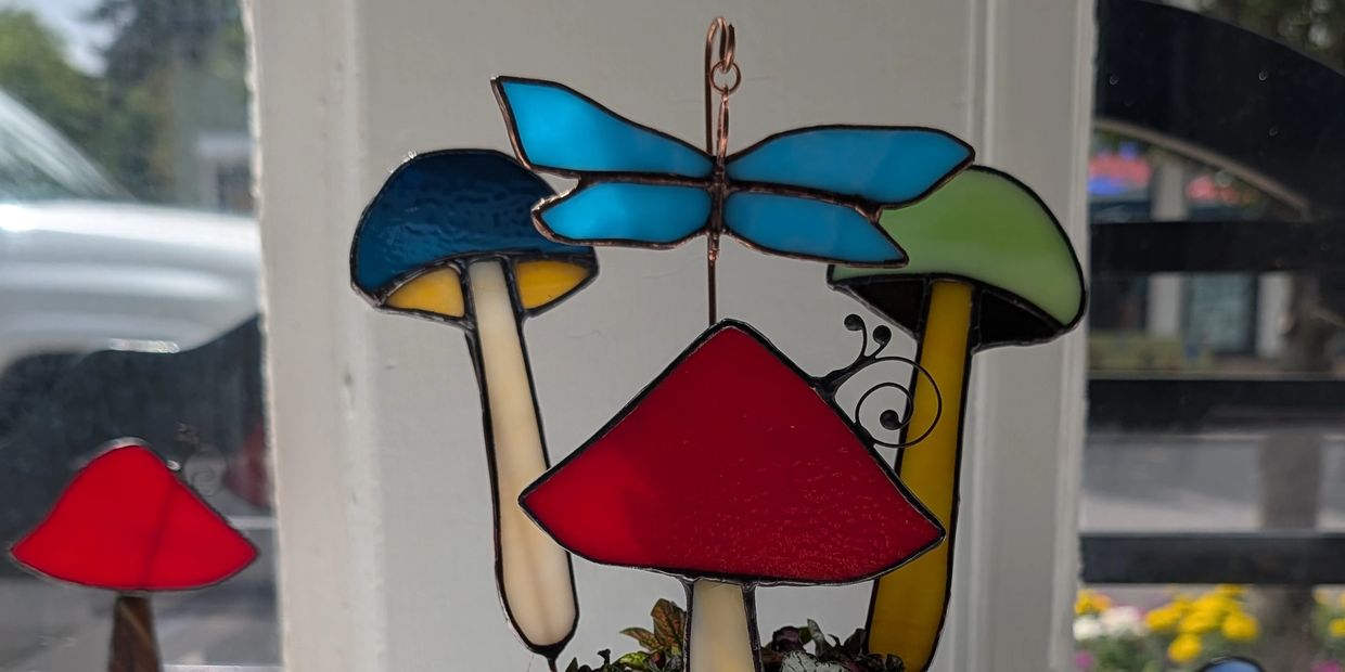 Stained glass mushrooms with a blue butterfly on a window.