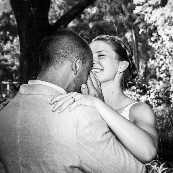 Couple embraces joyfully, woman smiling with ring visible.