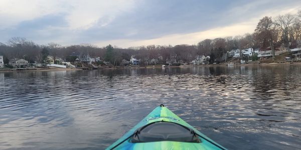 View from a kayak on calm lake water near a residential shoreline.