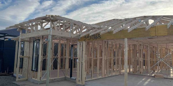 Wooden framework of a house under construction on a clear day.