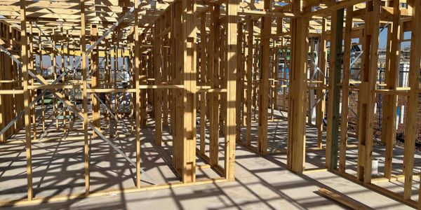 Wooden framework of a building under construction casting intricate shadows.