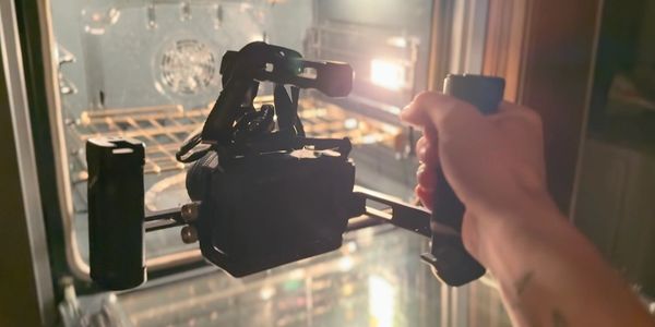 A person holding a camera rig inside an oven.