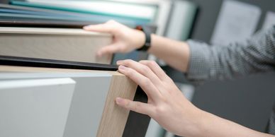 Hands touching cabinet door samples in kitchen showroom. Kitchen remodeling company Atlanta GA