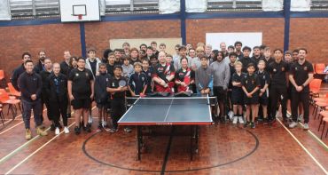 Group photo of a diverse table tennis team in an indoor gymnasium.