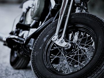 Close-up of a motorcycle front wheel in black and white.