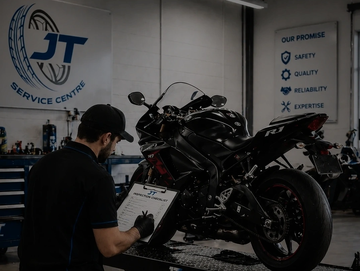 Technician inspecting a black Yamaha R1 motorcycle in a service center.