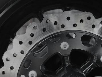 Close-up of a motorcycle brake disc with drilled holes for heat dissipation.