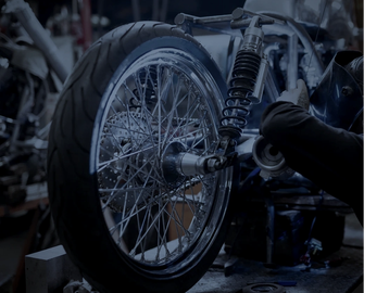 Person working on a motorcycle wheel and suspension system.