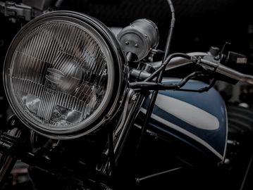 Close-up of a vintage motorcycle headlight and handlebar in black and white.