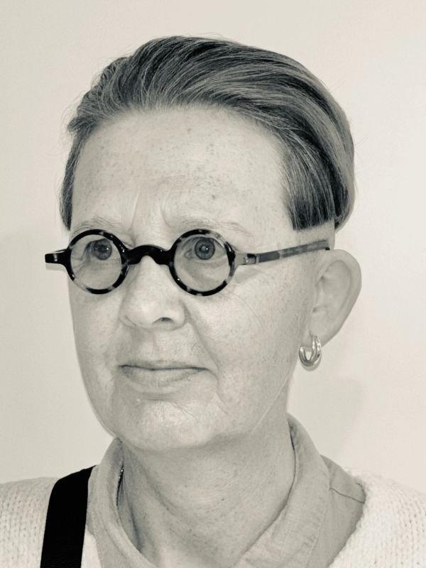Portrait of a person with round glasses and short hair.