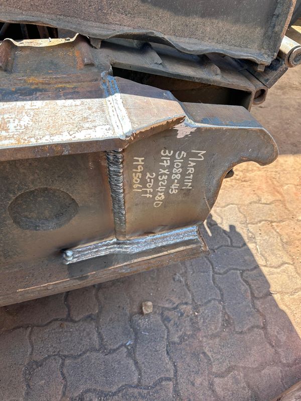 Close-up of a welded metal part with handwritten specifications on it.