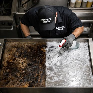 Person cleaning a heavily burnt cooking surface with spray cleaner and foam.
