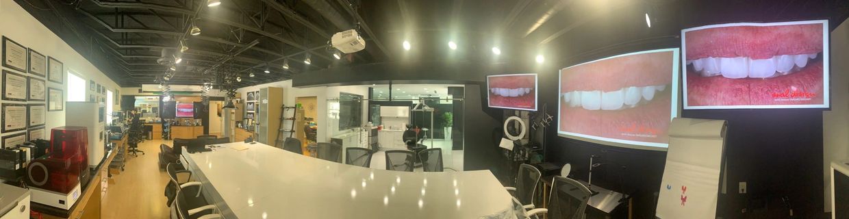Modern dental lab with large screens showing dental images and workstations.