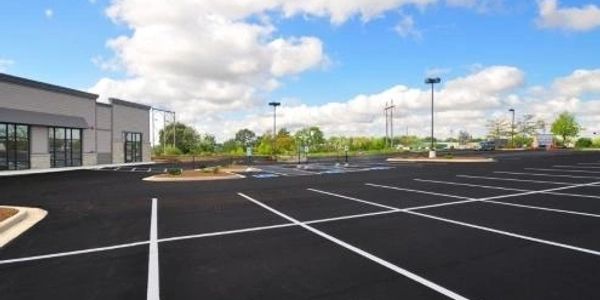 Empty parking lot outside a commercial building on a bright day.