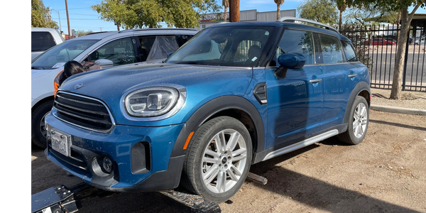 Blue Mini Cooper SUV on a car lift outdoors.