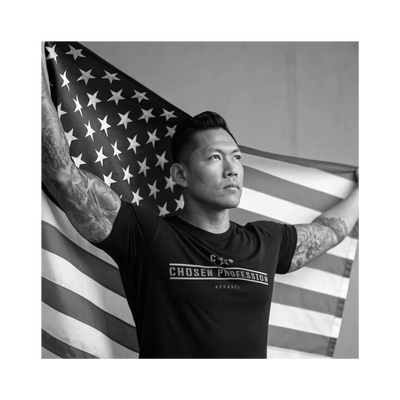 A man wearing a black shirt and holding the American flag in his hands 