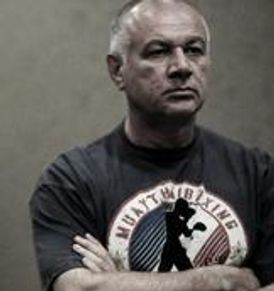 Man with arms crossed wearing a Muay Thai boxing t-shirt.