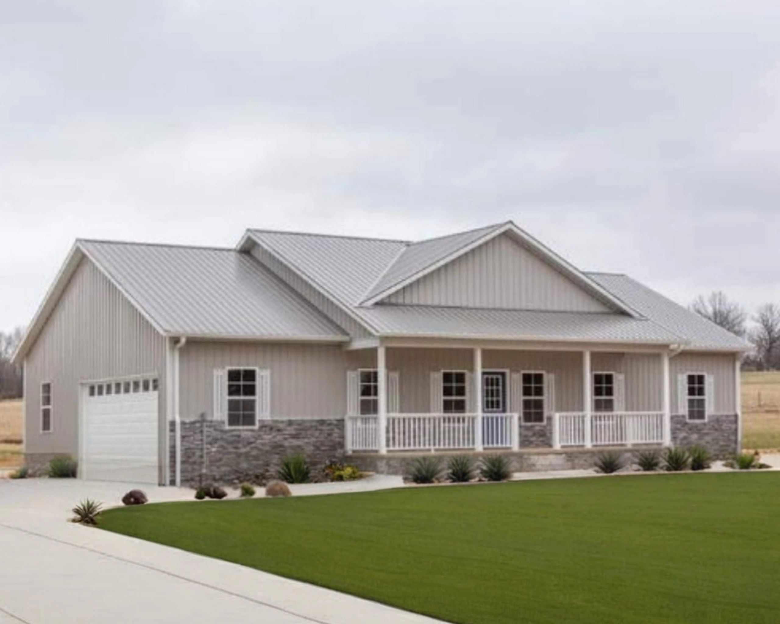 Modern house with gray metal roof and stone accents in a spacious yard.
