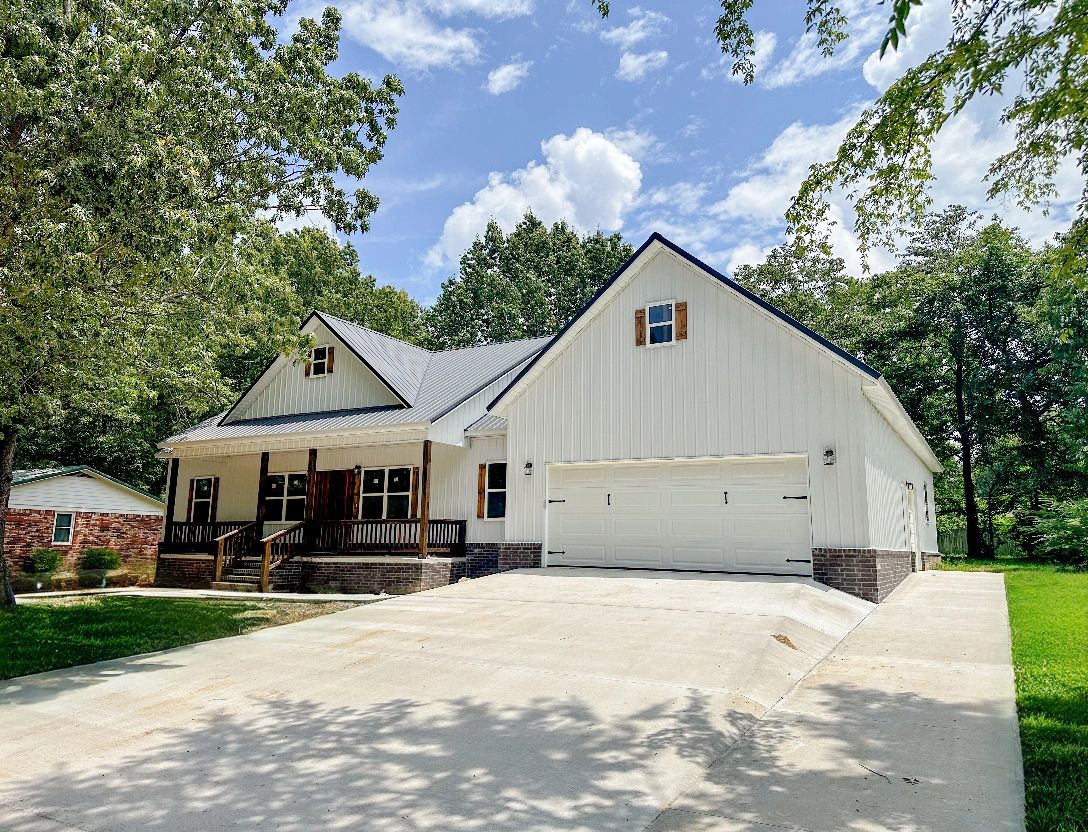 Modern white house with a spacious driveway and a two-car garage surrounded by trees.