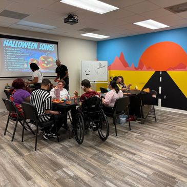 A picture of individuals sitting at a table working on a fall activity.