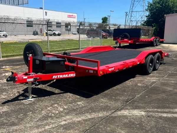 Red PJ trailer parked on concrete with a spare tire mounted at the front.