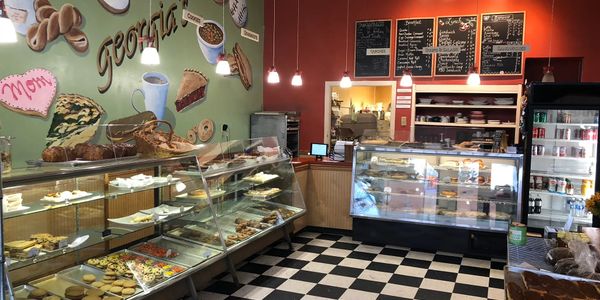 Cozy bakery with glass display cases filled with pastries and a menu on the wall.