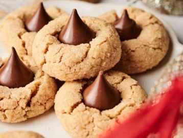 Close-up of peanut butter blossoms cookies with chocolate kisses on top.