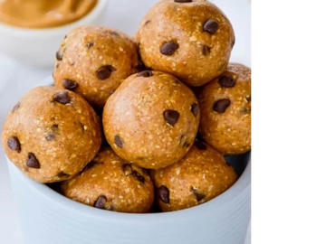 Bowl of chocolate chip energy bites with a creamy dip in the background.