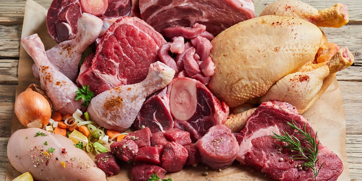 Variety of raw meats and poultry on a wooden surface.