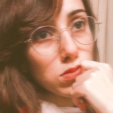 Close-up portrait of a woman with glasses and thoughtful expression.