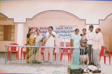 Group of people interacting on a stage with a banner behind.