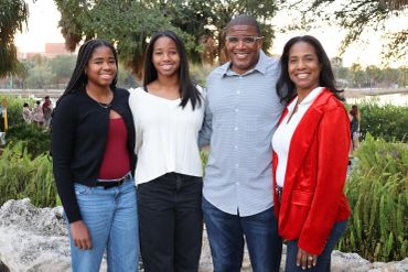 A smiling family of four posing outdoors.