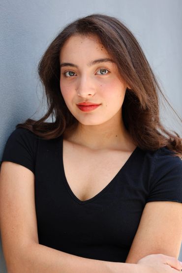 Young woman with brown hair and red lipstick wearing black top.
