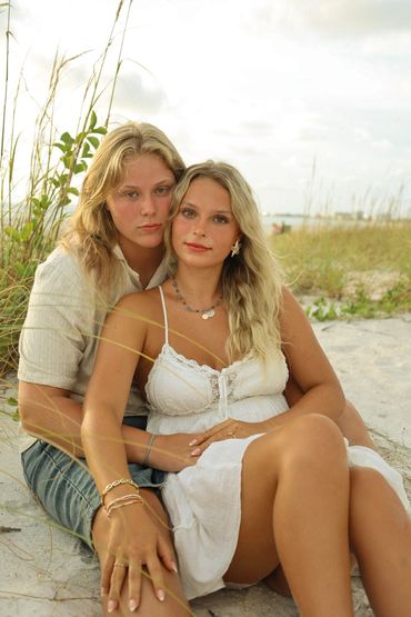 Couple sitting together on the beach with greenery around.