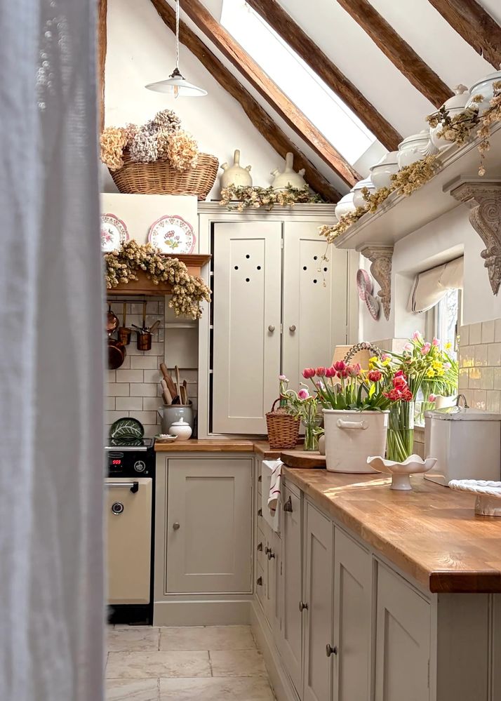 Layered country kitchen interior with wicker baskets, vintage ceramics and spring flowers