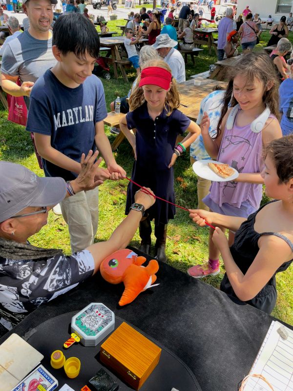 Kids interacting with a performer at an outdoor event.