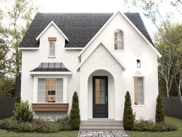 White cottage-style house with black roof and landscaped front yard.